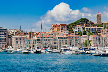 Luxury yachts, modern buildings, and sailboats in a beautiful Mediterranean marina view. Old city and harbor in Cannes, French Riviera, France.