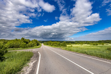 A road with a few trees in the background and a clear blue sky