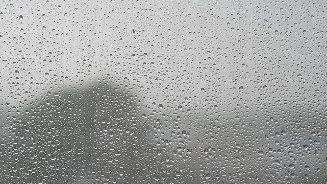 rain falling, raining outside window, focus on drops on window, summer rain in gloomy day in city