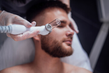 Caucasian man getting face peeling procedure in a beauty clinic, close up.