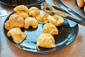 Sweet, delicious baked apple halves in a dark plate on a table in a self-service restaurant....