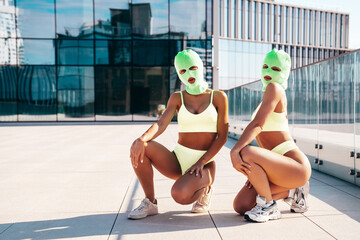Two beautiful sexy women in green underwear. Models wearing bandit balaclava mask. Hot seductive...