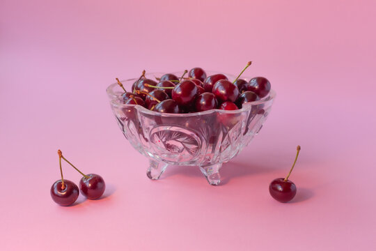 Juicy cherry in a crystal glass on a pink background.