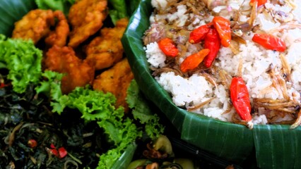 Nasi liwet is a typical Indonesian rice dish cooked with coconut milk, chicken stock and spices, giving the rice a rich, aromatic and savory taste.served on wooden basket