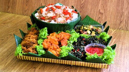 Nasi liwet is a typical Indonesian rice dish cooked with coconut milk, chicken stock and spices, giving the rice a rich, aromatic and savory taste.served on wooden basket