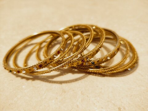 A set of metallic golden color bangles isolated background in sunlight, wedding female round rings golden brown collection bangles jewelry with gem stones photography