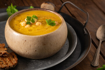 Pumpkin and chickpeas soup on brown rustic wooden background.