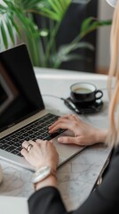 Close up of hands typing on a laptop keyboard in an office, working with a computer at a table