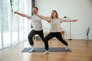 Warrior asana. Man and woman are doing yoga exercises at home