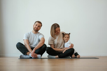 Obraz premium Cheerful people. Family of mother, father and daughter are doing yoga at home