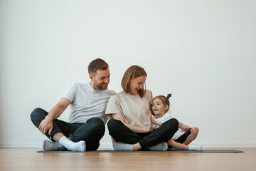 Family of mother, father and daughter are doing yoga at home