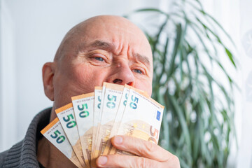satisfied man holding euros, euro money in fan, rejoices in success, anticipates what to spend it on, encouraging good financial behavior, economic awareness, money management