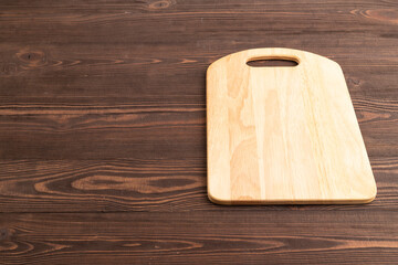 Empty rectangular wooden cutting board on brown wooden. Side view, copy space