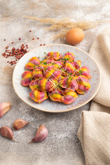 Rainbow colored dumplings with microgreen on brown concrete. Side view