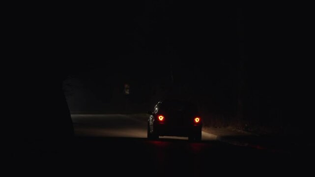 Night city traffic in foggy conditions with car driving down a street. The street is dark and the fog is thick, making it difficult to see, air pollution