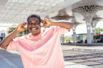 A man wearing headphones and a pink shirt is smiling