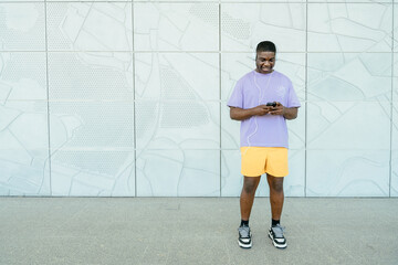 Cheerful young man using smartphone while walking on the street.