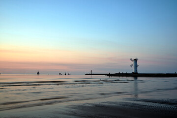 a breakwater with a watermark in the shape of a windmill in the town of Swinoujscie on the Baltic Sea