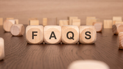 four wooden cubes with the text 'FAQS' on a brown background