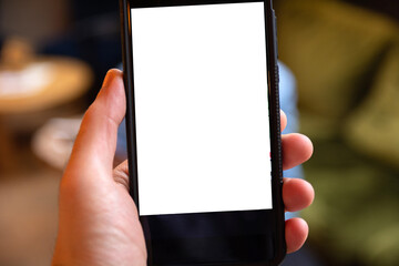 Close-up of a hand holding a mobile phone with a blank white screen for text or custom content. Blurred background