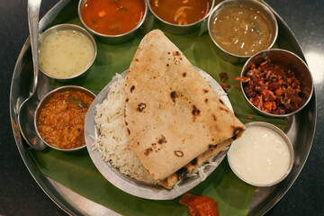 Indian vegetarian platter Thali meals. Having paneer butter masala dal makhani flat bread or naan and rice served in a steel plate and banana leaf Tamil Nadu, Bangalore Karnataka India.