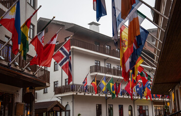 a modern mountain resort, where the architecture blends with the natural surroundings, complemented by vibrant flags that add a splash of color and international flair to the serene alpine environment
