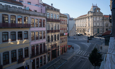 Obraz premium Morning light washes over a European cityscape, where historic buildings line the street leading to an ornate stone edifice, capturing a blend of daily life and architectural heritage.