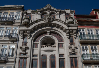 Fototapeta premium an ornate facade of a European-style building, located in an urban setting. arched windows with intricate designs, elaborate stone carvings flanked by traditional buildings with balconies.