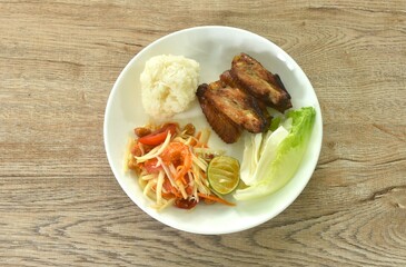 Som tum Thai spicy green papaya salad with roasted chicken wing eat couple sticky rice on plate 