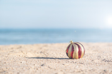 Obraz premium Christmas decorations bauble ball on sandy beach with sea background