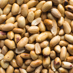 Overhead view of roasted peanuts on a white plate, flatlay of roasted peeled peanuts on a marble countertop