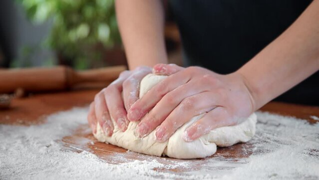 Housewife kneading dough for pizza or pie in kitchen, closeup view of female hands, cooking at home