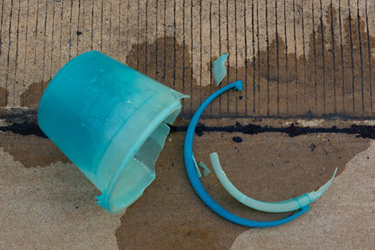 Shattered blue plastic bucket on wet concrete surface.