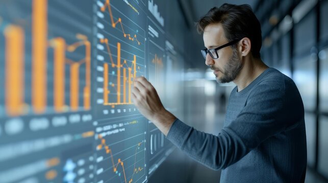 Focused man analyzing data on a futuristic digital screen, representing technology and data analysis in a modern workspace. - Powered by Adobe