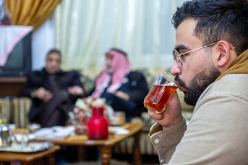 young male holding cup of tea with family gathering time indoors, enjoy time with family