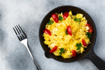 Healthy vegetarian breakfast . Scrambled eggs in pan with cherry tomatoes and parsley