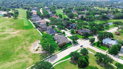 Suburban park with ample grassy space in upscale residential neighborhood row of two story mansion homes swimming pool, golf course community North Plano, Dallas Fort Worth Metroplex, aerial view