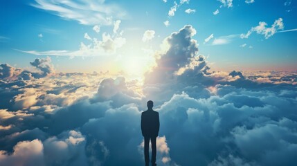 Obraz premium Above the clouds. Inspiring image of a lone businessman standing above the clouds, gazing towards a breathtaking sunrise. Perfect for themes of ambition, success, and leadership.