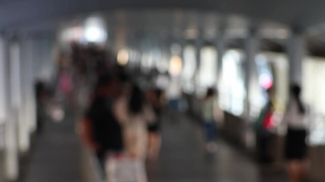 Bokeh view of passengers and blurred lights at Chong Nonsi BTS skytrain station in Silom district, Bangkok, Thailand.