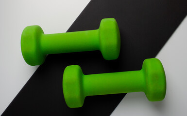 Green female dumbbells for sports on a black and white background