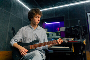 in the recording room equipment the sound of music a handsome young guy plays an electric guitar...