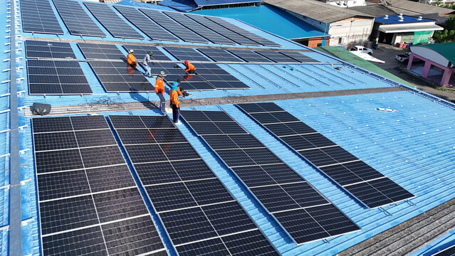 Aerial top view of Engineering technician is a professional trained in skills and techniques installing solar photovoltaic panels system on power industrial factory roof, Engineering concepts.