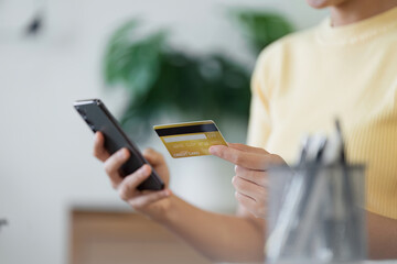 Woman Using Credit Card for Online Shopping on Smartphone in Modern Home Setting