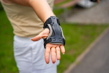 Close up view of hand in protection glove of roller skater woman in inline skates rollerblading in...