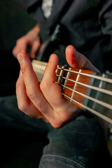 close up in the equipment of a recording room handsome man with a beard and tattoos plays an electric guitar plucks the strings choosing the right note