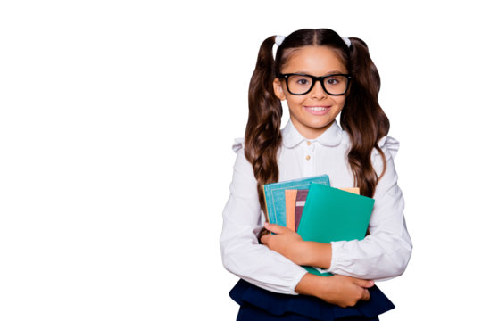 Glad positive nice smart cute small little girl with curly pigtails in white blouse shirt and blue skirt, carrying, keeping, hugging big book pile, copy-space. Isolated over black background