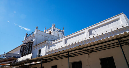 a bright blue sky over a white stucco building with intricate blue tile work and traditional Spanish architectural features, a location within a historic European city.