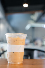 Cold latte coffee in a plastic glass on wood table
