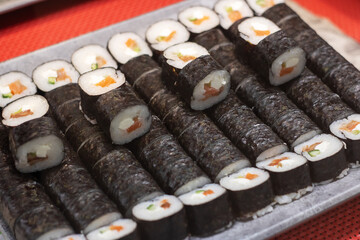 A tray with sushi rolls displayed on a vibrant red table