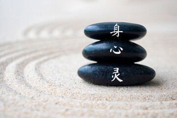 Close up view of body, mind and spirit in Chinese character on zen stones with sand background